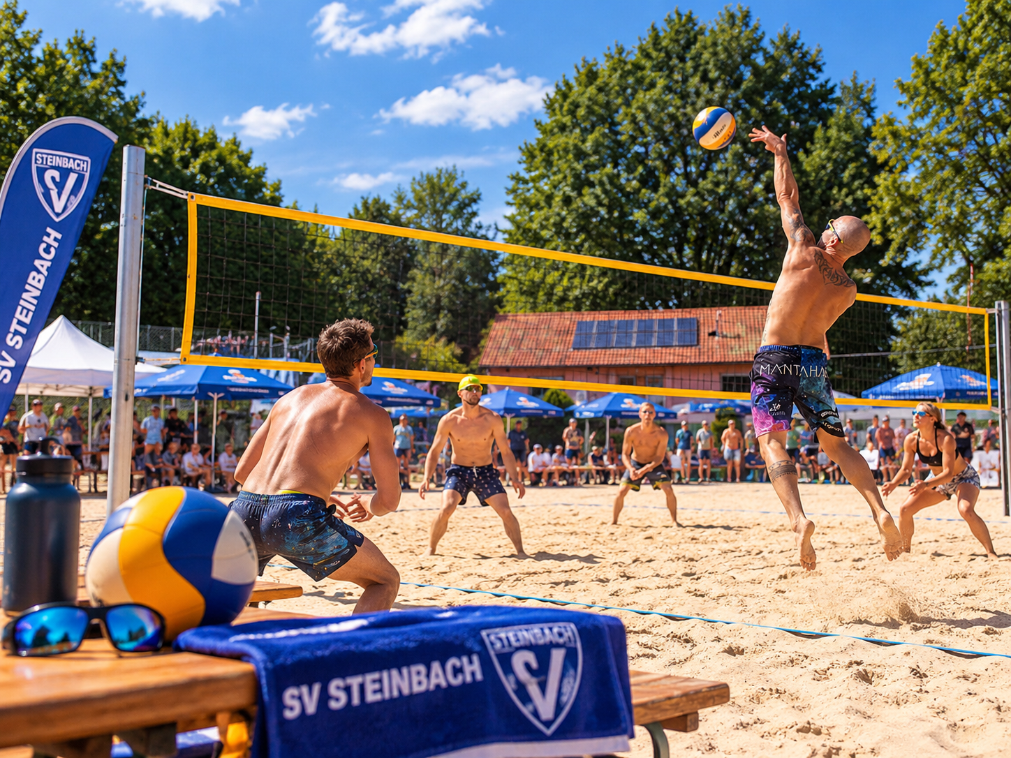Beachvolleyballszene mit einem Spieler beim Angriff am Netz, Zuschauern und blauen SV-Steinbach-Fahnen im Sonnenschein.